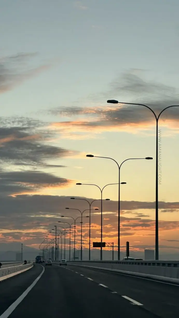 Long stretch of LED street lighting poles along a highway bridge at sunset – modern classic design for smart city infrastructure.